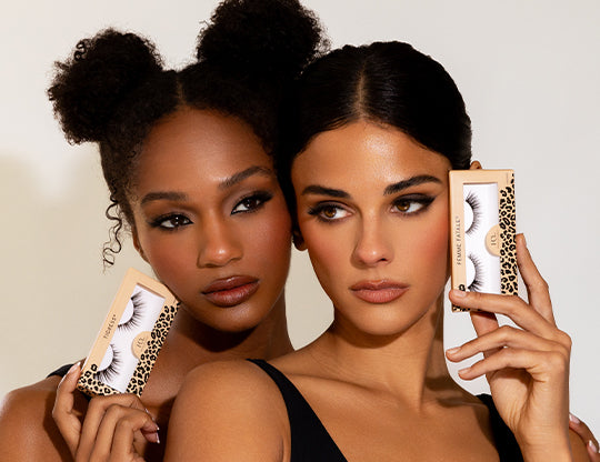 Two models wearing Feline Collection false eyelashes and holding the packaging.