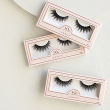 Three Iconic false eyelashes in packaging on a textured background.